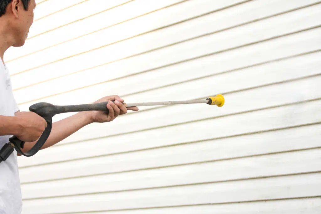 Man cleaing the side of a house 