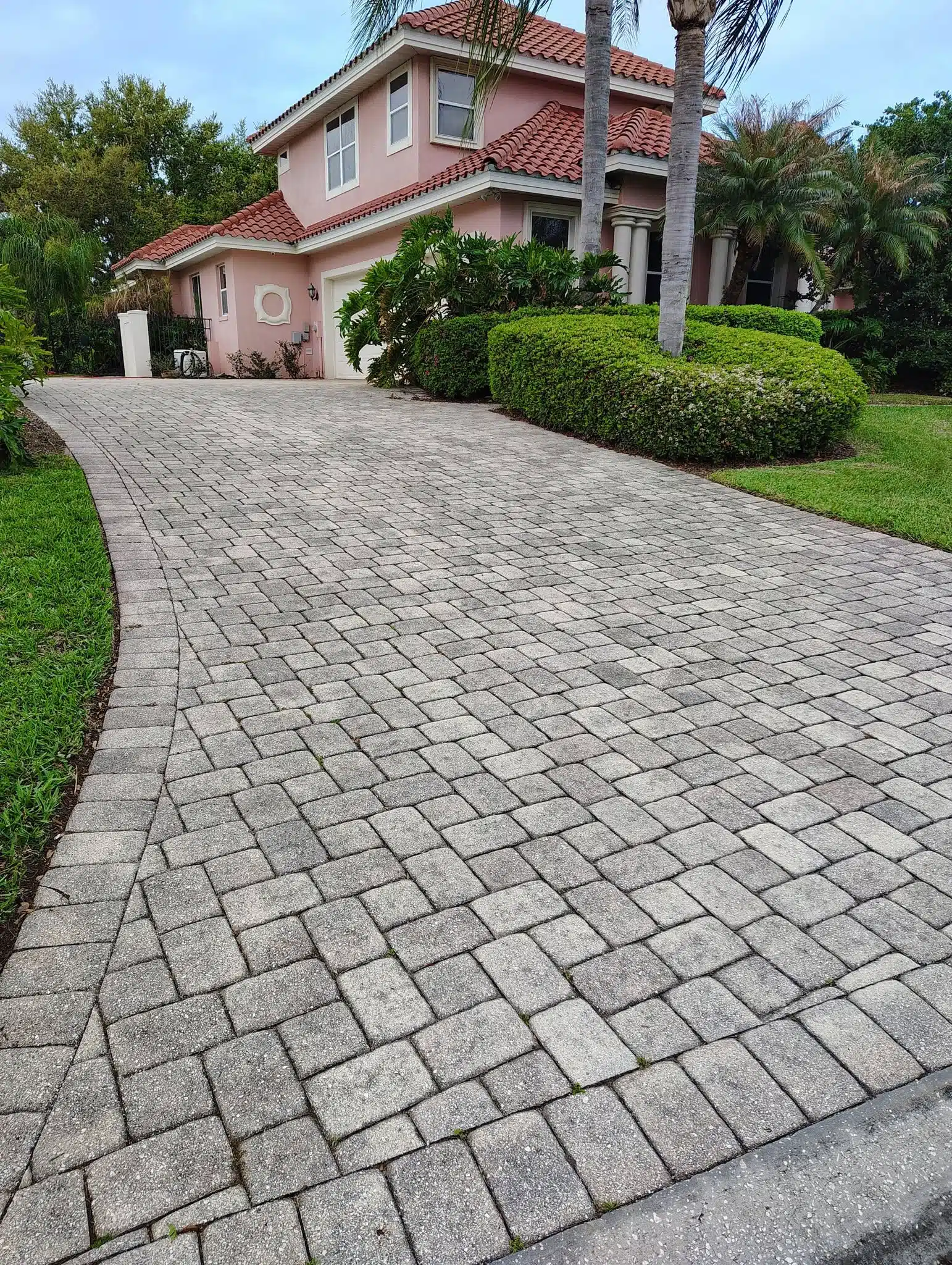 Pink stucco house with red tile roof driveway